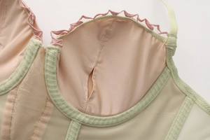 Dettaglio ravvicinato del tessuto a rete traspirante e pizzo sulla lingerie a corsetto verde