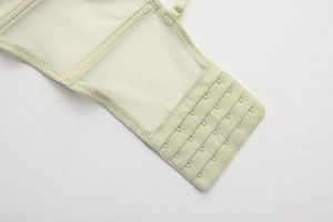 Dettaglio della chiusura posteriore a quattro file sul reggiseno a rete verde