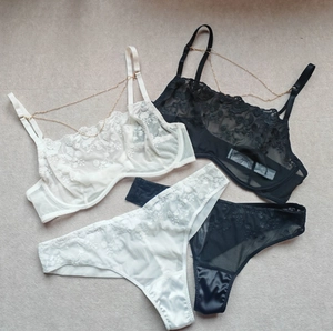 Close-up of sheer lace bras with floral embroidery and decorative gold chains
