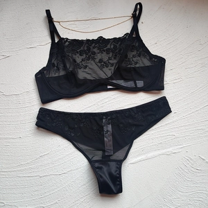 Detailed macro shot of black floral embroidery and gold chain on lace lingerie set