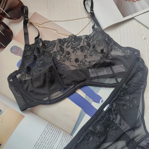 Detailed close-up of black floral embroidery lace lingerie set with gold chain detail