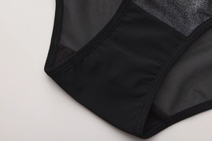 Dettaglio macro di lingerie in rete nera con tessuto argento e cuciture rinforzate a zigzag
