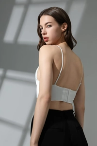 Dettaglio posteriore del reggiseno in raso bianco con spalline sottili e ganci sul retro
