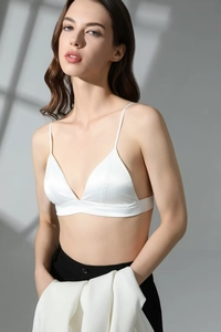 Detail of white satin triangle bralette featuring thin straps and wireless silk texture