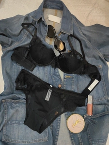Detail of black floral lace bra set with washing label showing size 75B and M on denim background
