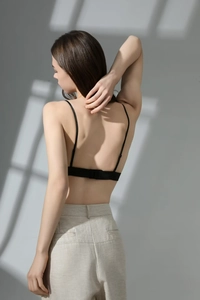 Detail of thin adjustable straps and back hook closure on a seamless black bralette