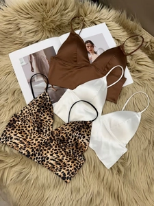 Three V-neck satin crop tops in brown, white and leopard print on a plush background
