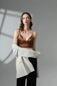 Detail of a brown satin V-neck camisole paired with a chic white blazer for women