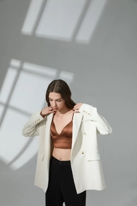 Detail view of a white double-breasted blazer paired with a brown satin camisole top