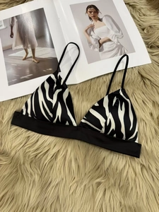 Flat lay of zebra print triangle bralette with slim straps on a plush carpet background