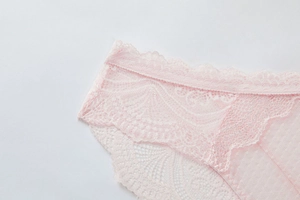Close-up detail of light pink floral lace and breathable mesh fabric on panty