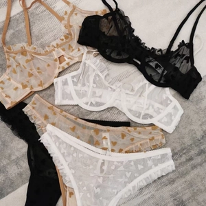 Detail view of lace lingerie set with heart print mesh and ruffled edges on carpet