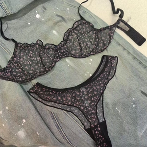 Flat lay of black mesh lace floral bra and thong set on blue denim jacket background