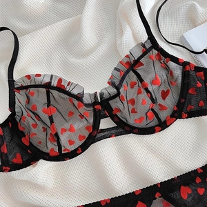 Dettaglio del set lingerie in rete nera con stampe a cuore rosso e bordi in pizzo arricciato