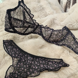 Detail of sheer black floral lace lingerie set with ruffled edges and mesh embroidery