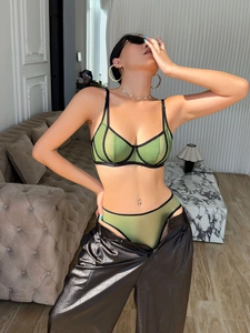 Detail of olive green sheer mesh lingerie set with black trim on a modern sofa