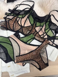 Detailed flat lay of French leopard print lace bra and panty sets on soft textures