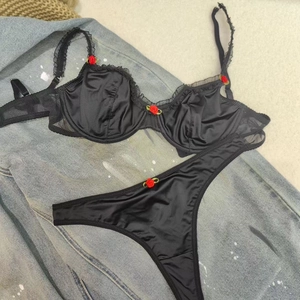 Lace bra set with red roses and sheer trim on satin fabric in flat lay view