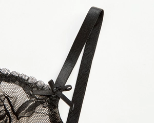 Detailed macro view of black floral lace bra strap with a delicate decorative bow