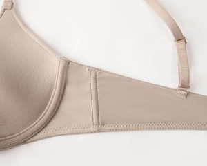 Detail of nude seamless bra with smooth fabric texture and adjustable shoulder straps
