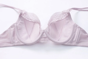 Close-up of pink lace bra with soft underwire, mesh edges, and bow strap detail