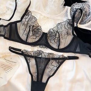 Macro view of delicate black rose embroidery and sheer mesh lace fabric on the bra