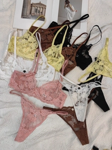 Flat lay detail of multi-color floral lace bras and thongs with daisy embroidery