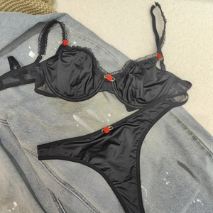 Ensemble lingerie en satin noir avec détails roses rouges sur fond denim