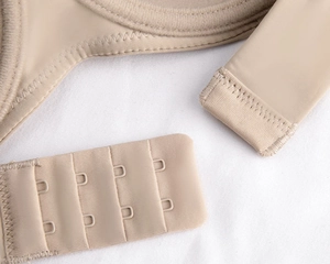 Detail of seamless beige bra with four-row hook-and-eye closure and smooth fabric