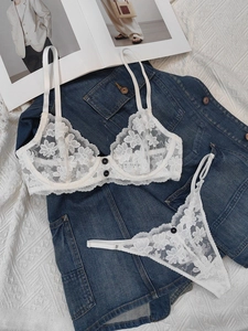 Flat lay of white floral lace lingerie set with black buttons on denim jacket