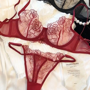 Flat lay of dark red mesh lingerie set with intricate rose embroidery and pearls