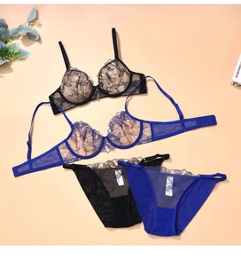 Dettaglio in piano di completi intimi in pizzo nero e blu con ricami floreali fini