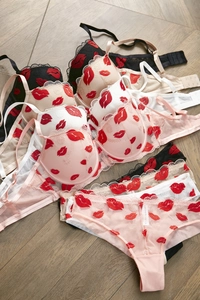 Flat lay of multiple color embroidered lace lingerie sets featuring red lip patterns