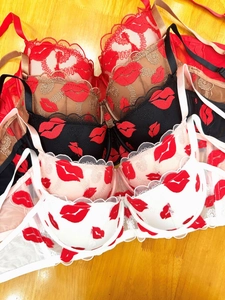 Macro shot of French lace embroidery with red lip patterns on these push-up bras