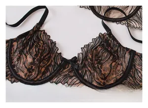 Dettaglio reggiseno in pizzo nero con bordi smerlati e un fiocco di raso centrale