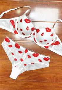 Detailed view of white mesh lingerie set with red lip embroidery and delicate lace trim
