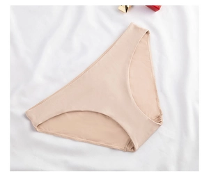 Flat lay of seamless beige microfiber panties on white fabric background with cosmetics