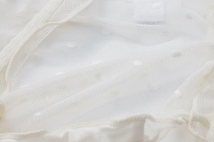 Dettaglio ravvicinato del tessuto a rete bianco con pois e cucitura elastica