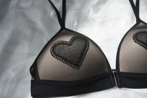 Close-up of black lace triangle bra with heart embroidery and front buckle design