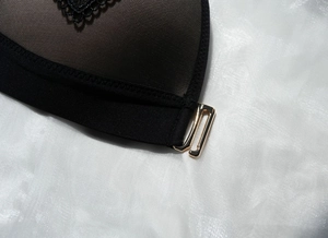 Macro detail of black lace lingerie showing fine mesh and premium gold metal clasp