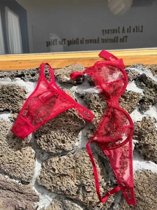 Détail d'un ensemble de lingerie en dentelle rouge sur une surface de pierre rustique