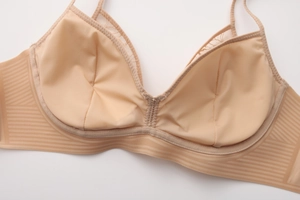 Detail of beige seamless wireless bra featuring striped elastic band and lace trim