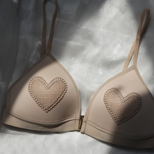 Lace triangle cup bra with heart embroidery and front buckle on silk background