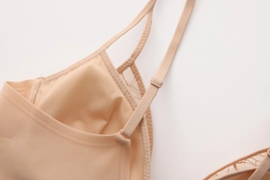 Detail of thin shoulder straps and delicate lace stitching on beige wireless bra