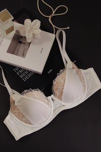Détail d'un soutien-gorge en dentelle blanche avec broderies et empiècements en satin