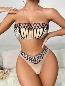 Dettaglio del ricamo geometrico traforato sul set di lingerie beige stile francese