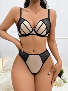 Dettaglio del set intimo in rete nera con fodera beige e fibbie dorate metalliche
