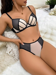 Dettaglio del set di lingerie in mesh beige con linee nere e accenti in metallo dorato