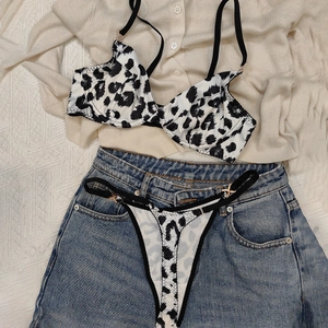 Flat lay of leopard print lingerie set with black straps and gold buckles details