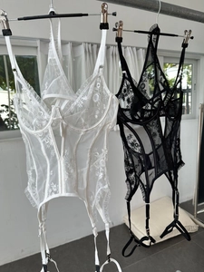 Detail of sheer lace lingerie set with floral embroidery and garter straps in white and black
